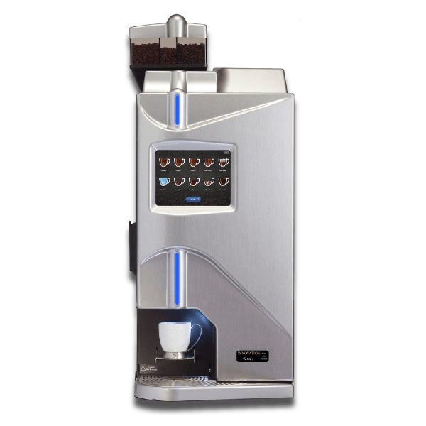 A modern silver coffee vending machine with a touchscreen drink menu, blue LED lighting, and a white cup placed under the dispenser, with whole coffee beans visible in the top hopper.