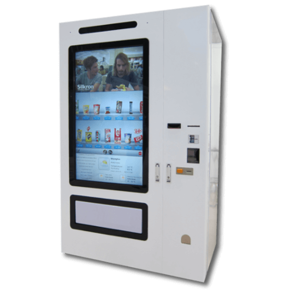 A modern white vending machine featuring a large full length touchscreen displaying snack options and a video at the top. Payment slots and buttons are on the right side of the machine.